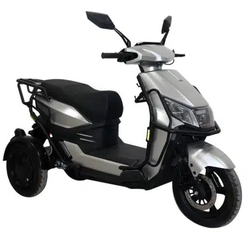 De For Motion Trice - nieuwste Trike scootmobiel is een zilverkleurige driewielige elektrische step met een zwarte zitting, achteruitkijkspiegels en beschermbeugels, afgebeeld vanaf de voorzijde op een witte achtergrond.