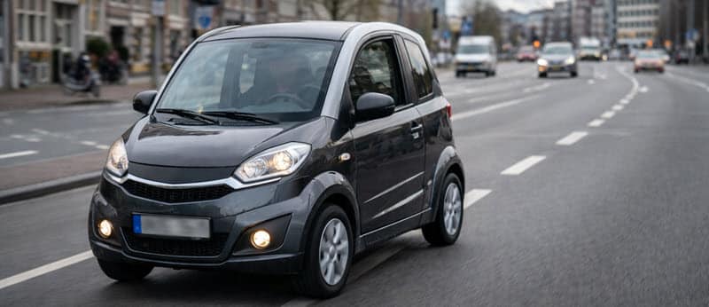 Overdekte 45 km auto microcar op de weg, met focus op stabiliteit en zichtbaarheid.
